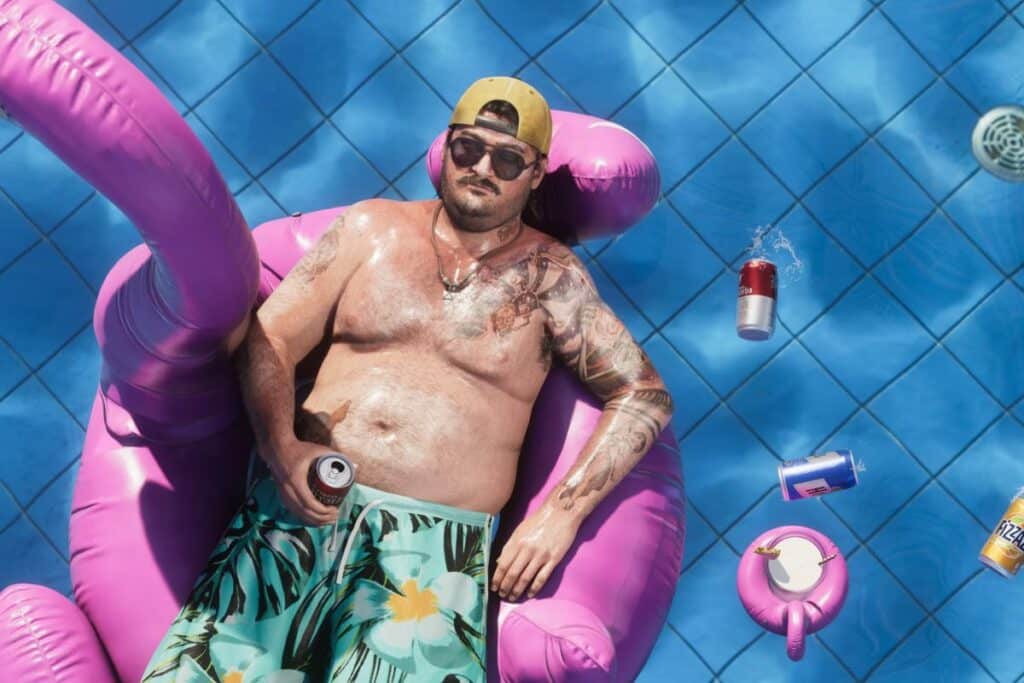 Homme relaxant sur une bouée rose dans une piscine.