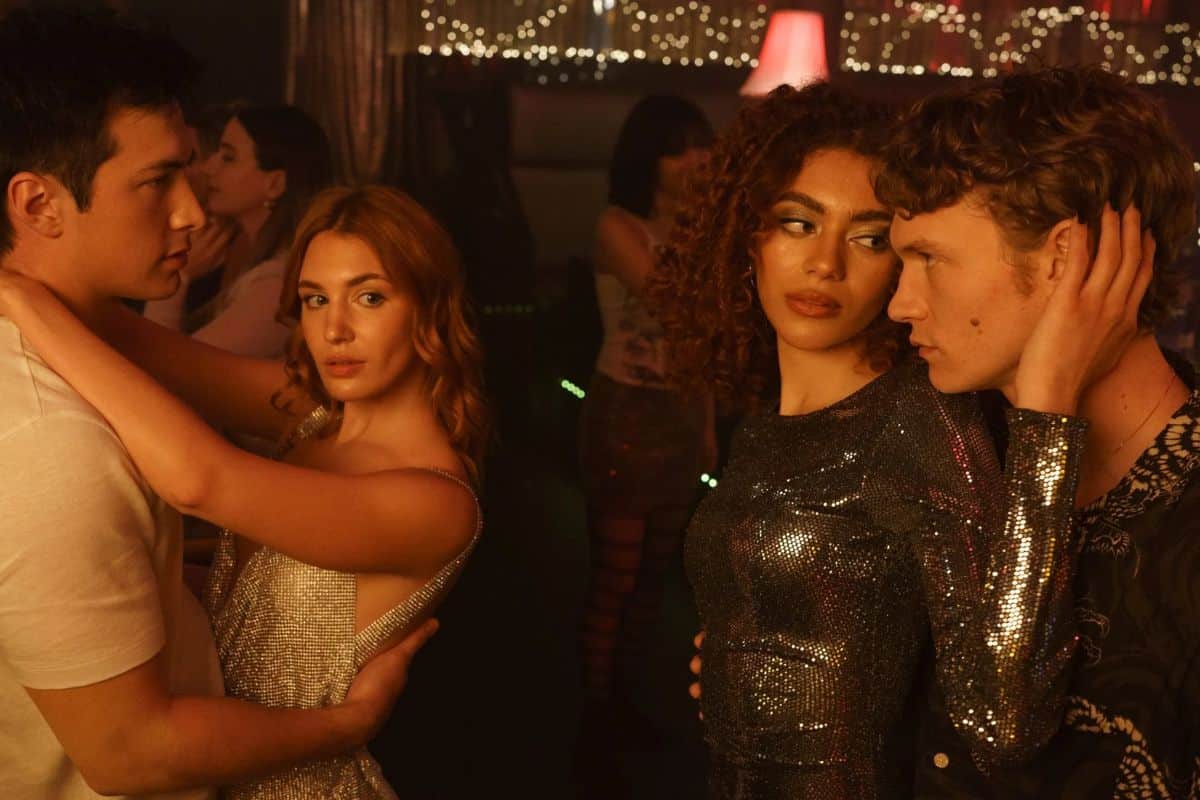 Quatre personnes dansent en couple dans un club.