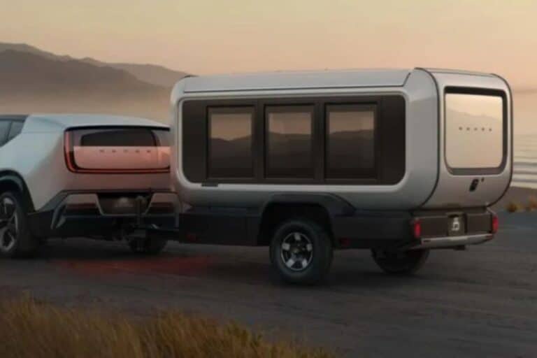 Voiture électrique tractant une caravane sur route côtière.