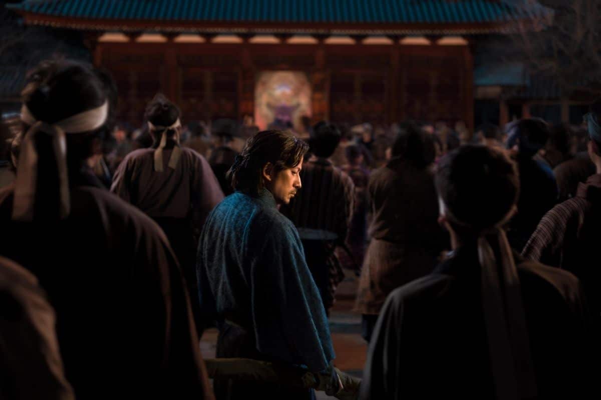 Homme en kimono bleu dans une foule.