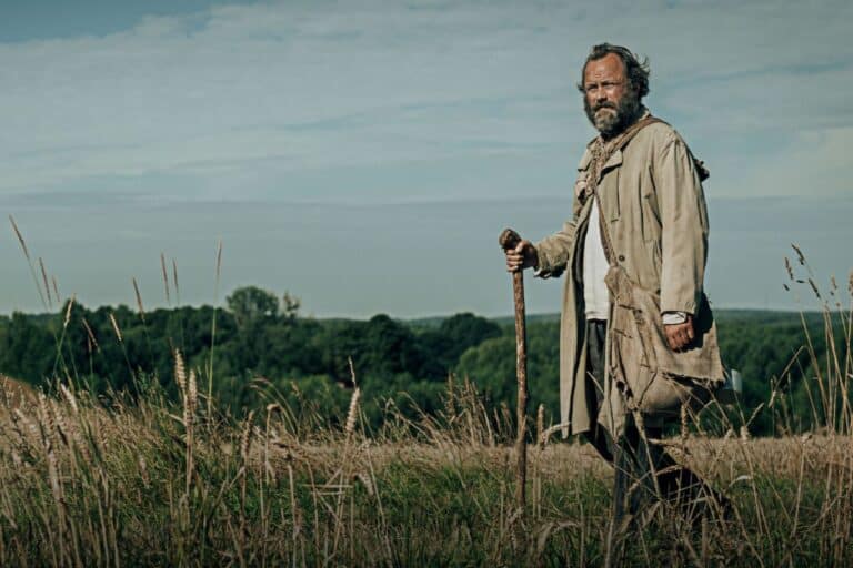 Homme marchant dans un champ avec bâton.