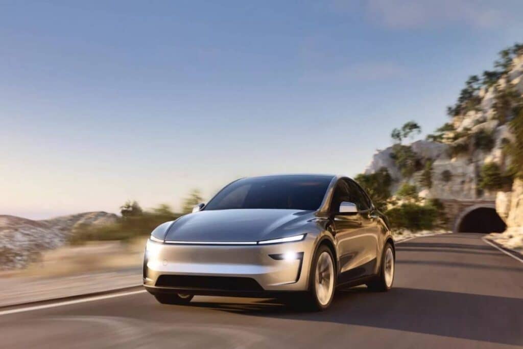 Voiture électrique argentée roulant sur route de montagne.