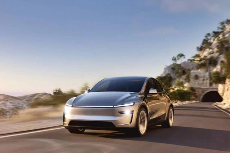 Voiture électrique argentée roulant sur route de montagne.