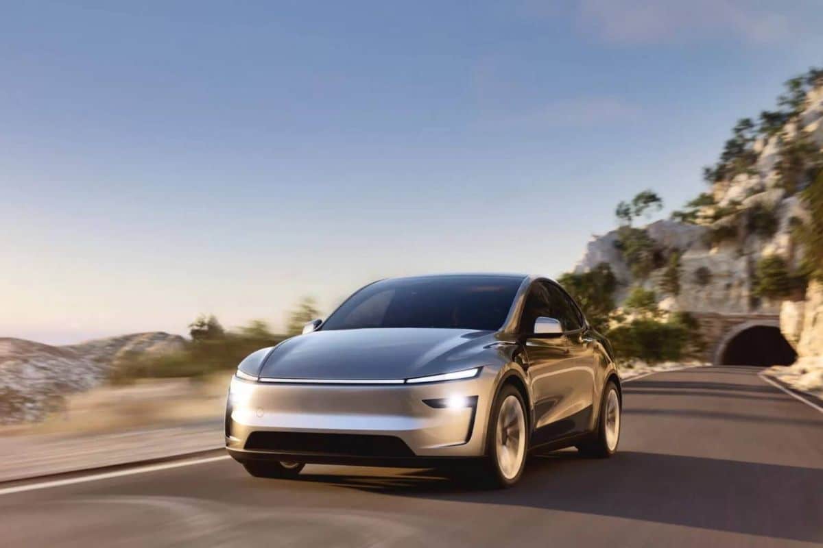 Voiture électrique argentée roulant sur route de montagne.