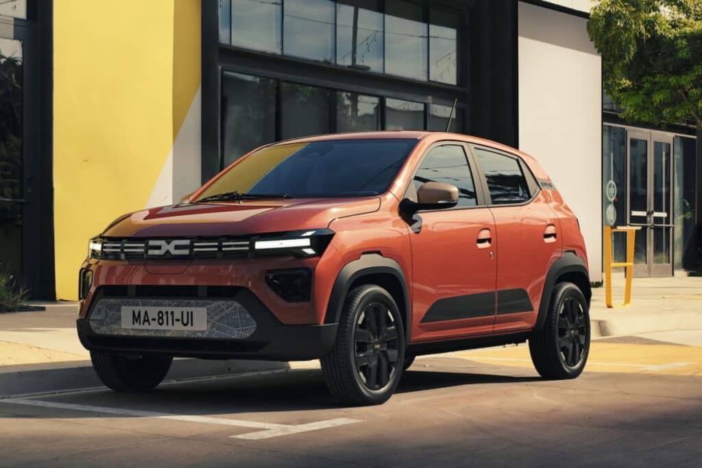 Voiture orange garée devant bâtiment moderne.