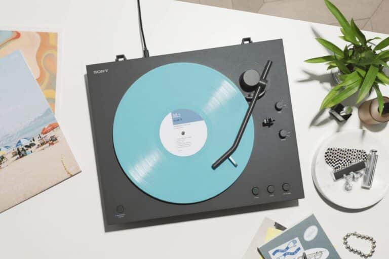 Platine avec disque vinyle bleu sur table blanche.
