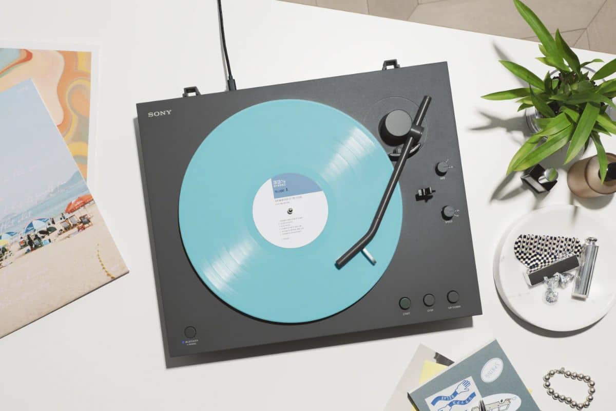 Platine avec disque vinyle bleu sur table blanche.