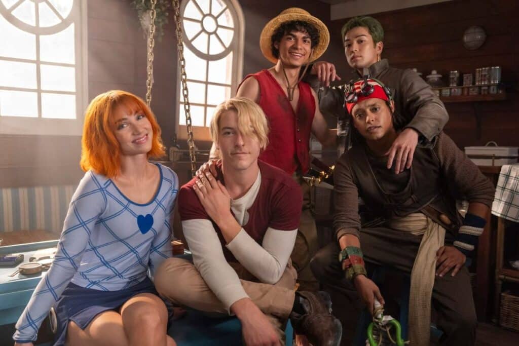 Cinq personnages costumés posent ensemble souriants.