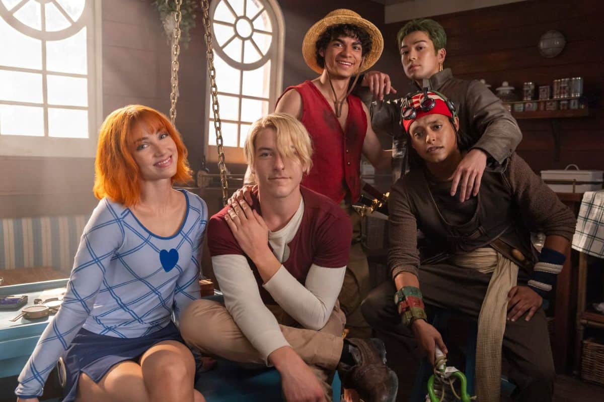 Cinq personnages costumés posent ensemble souriants.