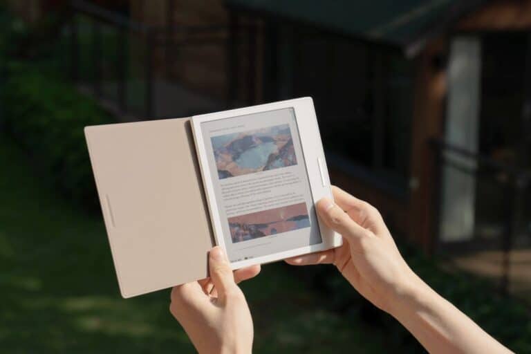 Personne tenant une liseuse ouverte en extérieur.