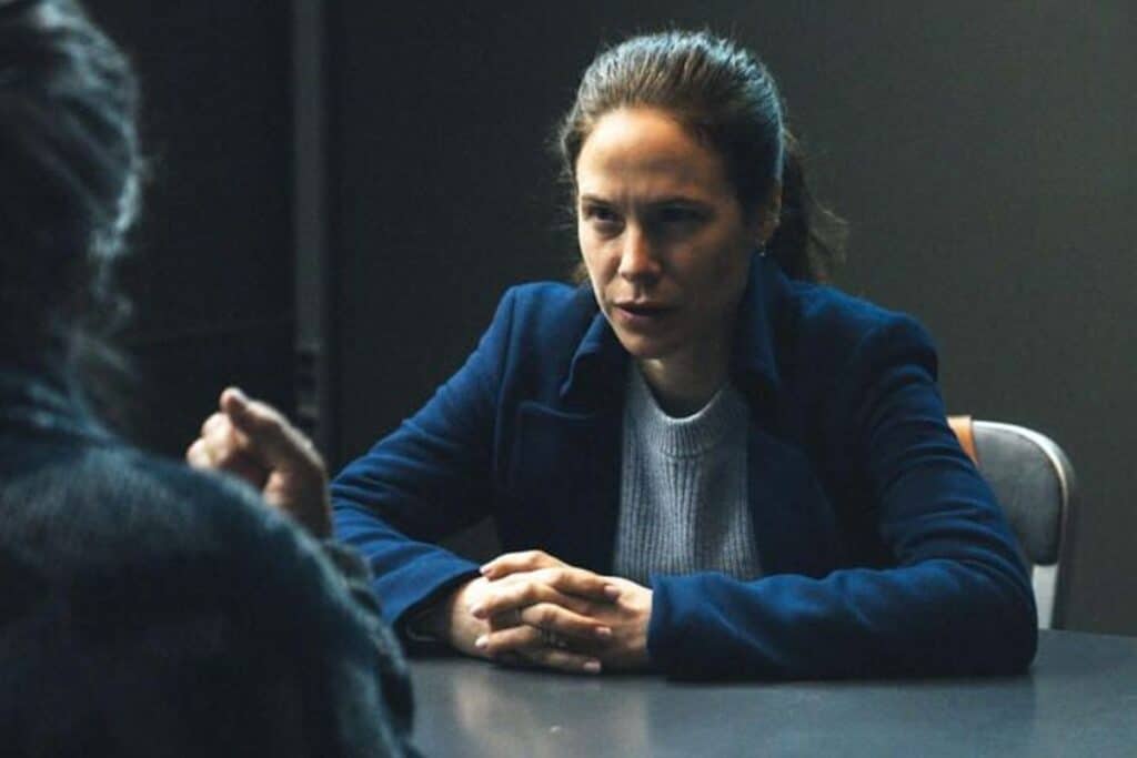 Femme interrogée sérieusement à une table.