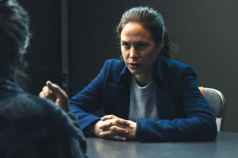 Femme interrogée sérieusement à une table.