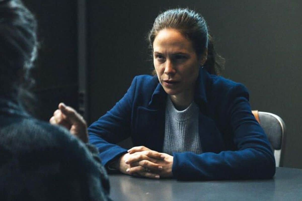 Femme interrogée sérieusement à une table.