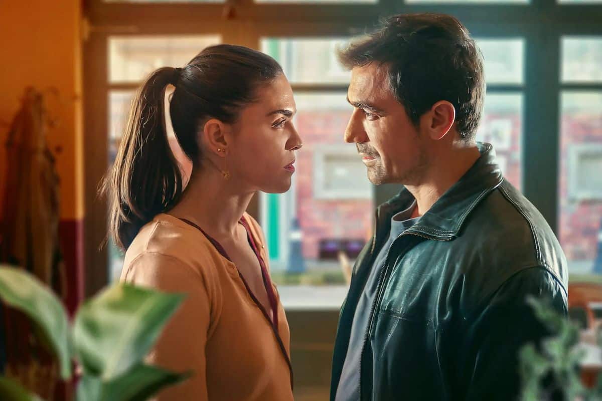 Deux personnes discutent intensément dans une pièce éclairée.