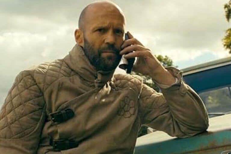 Homme au téléphone devant une voiture ancienne.