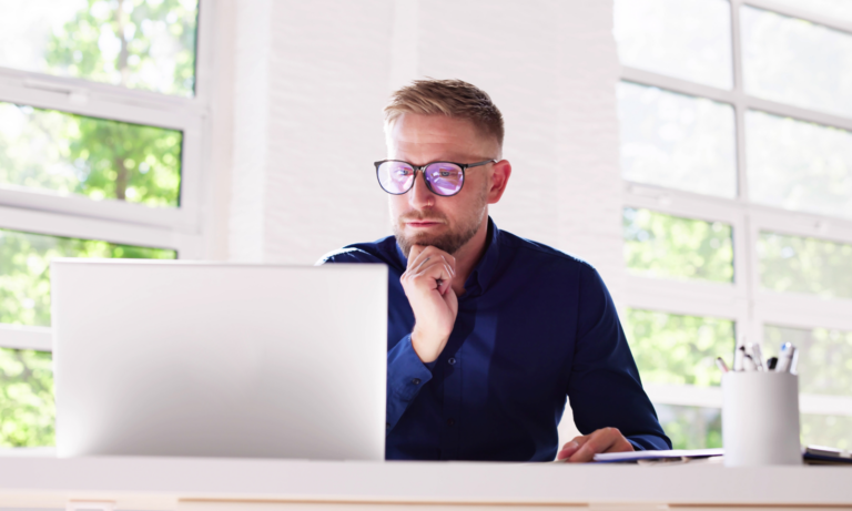 Homme concentré travaillant sur ordinateur portable lumineux.