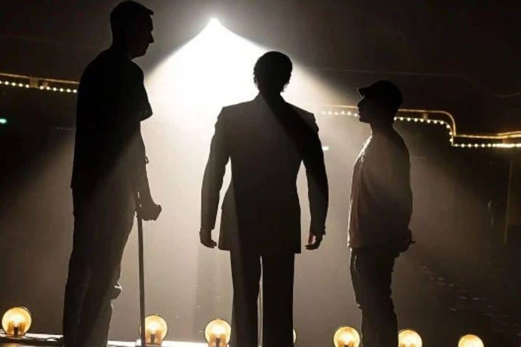 Silhouettes de trois personnes sur scène éclairée.