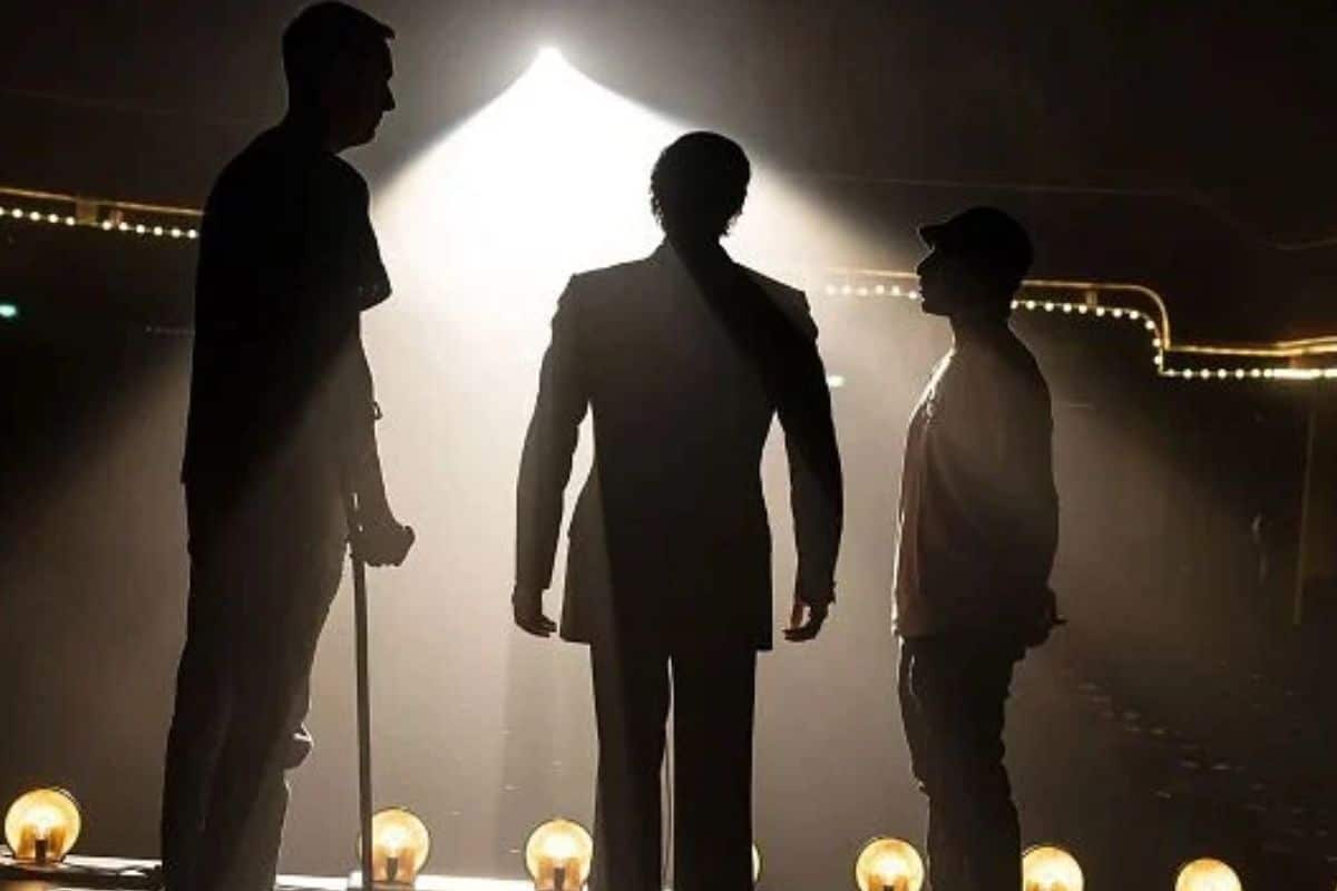 Silhouettes de trois personnes sur scène éclairée.