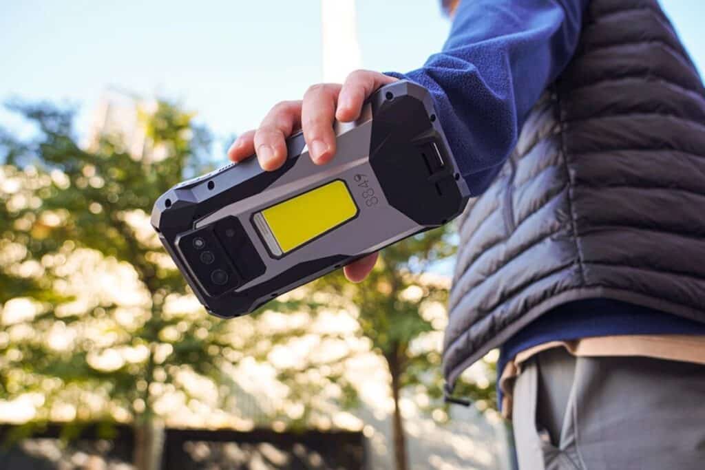 Homme tenant un smartphone robuste en extérieur.