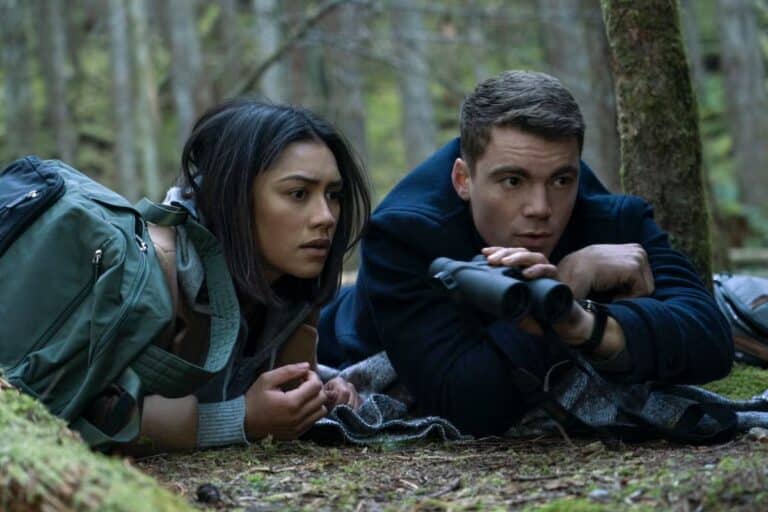 Deux personnes allongées observant dans une forêt.